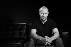 Tim Ferriss sitting on a tufted leather couch.