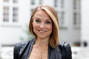 Esther Perel standing outside in front of a white building.