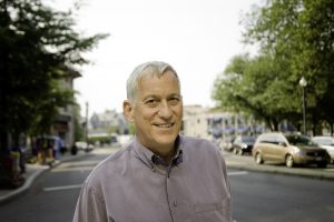 Walter Isaacson standing outside in front of a small-town street.