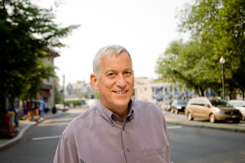 Walter Isaacson standing outside in front of a small-town street.