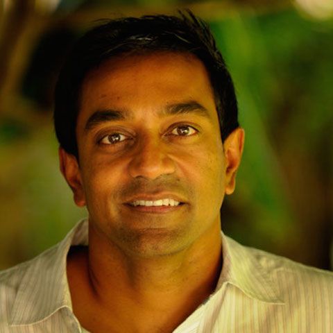 M. Sanjayan standing outside in front of lush plants.