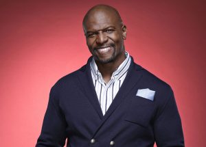 Terry Crews in front of a red backdrop.