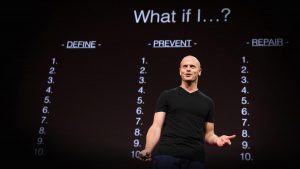 Tim Ferriss giving his Fear-Setting TED talk in front of a slide that has "What if I?" at the top and 3 columns below it: Define, Prevent, and Repair.