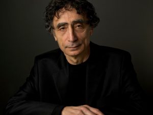 Dr. Gabor Maté sitting front of a dark gray backdrop.