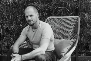 Tim Ferriss sitting in a large patio chair in front of a patch of bamboo.
