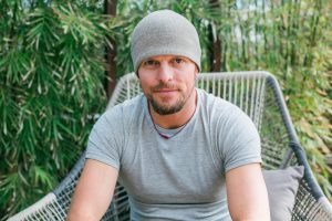 Tim Ferriss sitting in a large patio chair in front of a patch of bamboo.