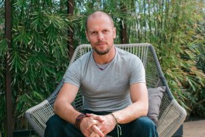 Tim Ferriss sitting in a large patio chair in front of a large patch of bamboo.