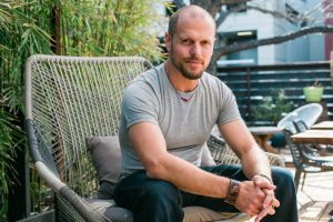 Tim Ferriss sitting outside in a large patio chair in front of bamboo.