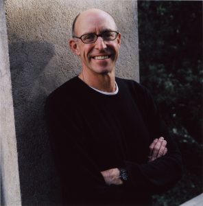 Michale Pollan outside and leaning against a large, vertical slab.