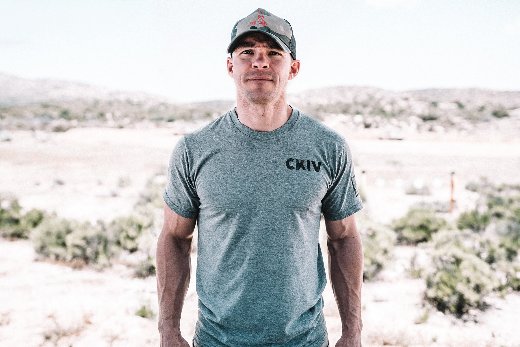 Nick Norris in a CKIV t-shirt and camo ball cap, standing outside in desolate wilderness.