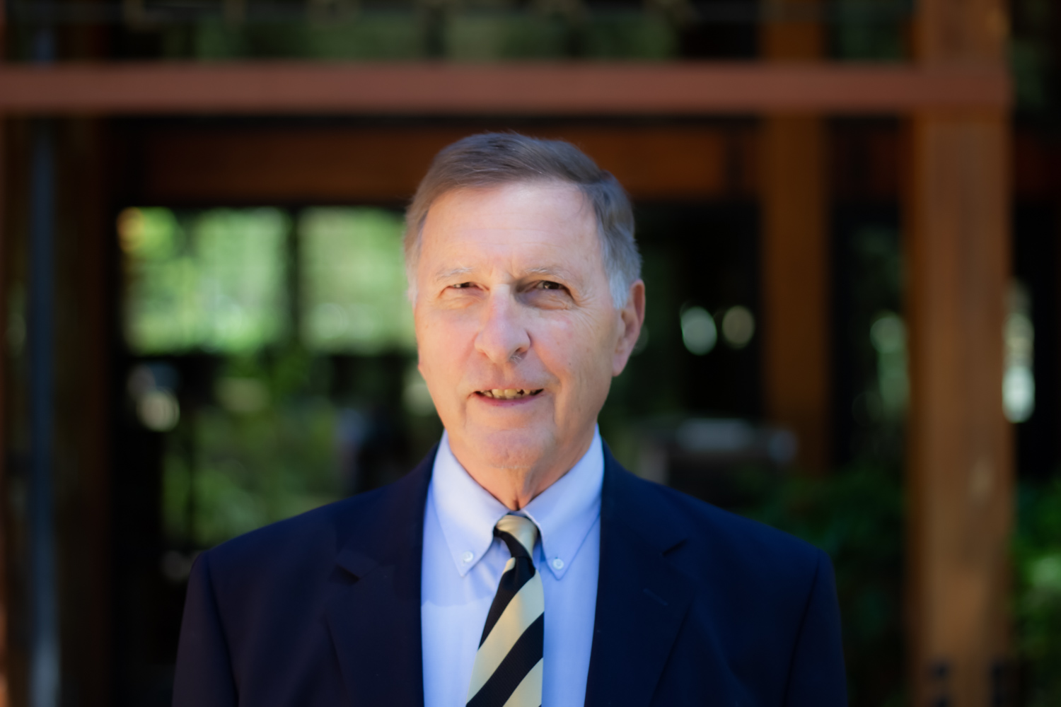Ed Zschau standing outside in front of a wood and glass building.