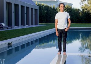 Brian Grazer in jeans and a white t-shirt, standing on the hot tub wall of his pool.