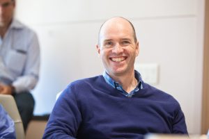 Ben Horowitz in a blue shirt and sweater, sitting and smiling.