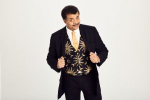 Neil deGrasse Tyson in a dark suit with a sun and moon vest.