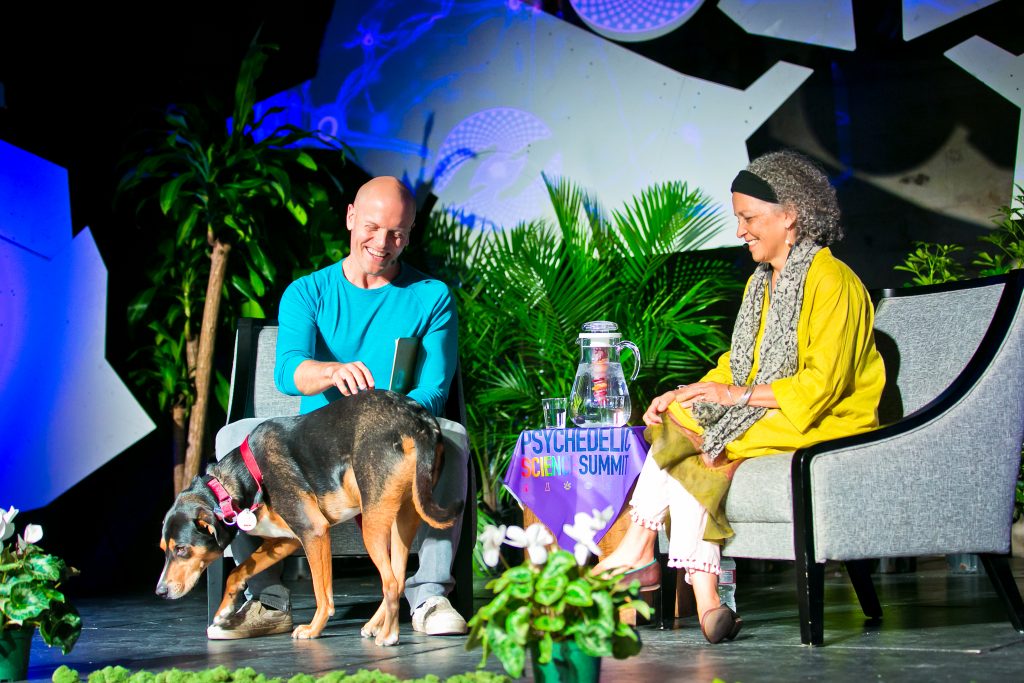 Tim Ferriss petting his dog Molly while onstage with Marcela Ot'alora at the MAPS Psychedelic Science Summit.