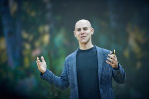 Adam Grant speaking onstage in a blue sportcoat.