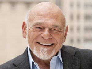Sam Zell smiling in front of a large building.
