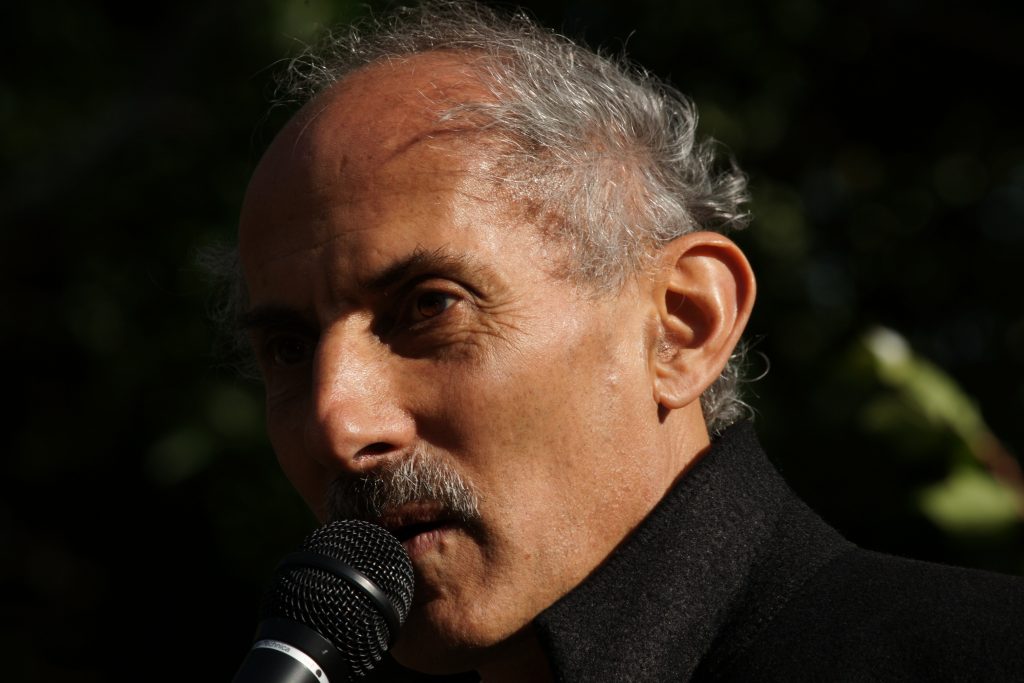 Jack Kornfield speaking at a microphone outside.