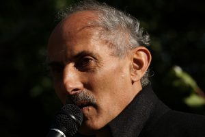Jack Kornfield speaking at a microphone outside.