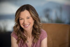 Lori Gottlieb sitting on a couch and smiling.