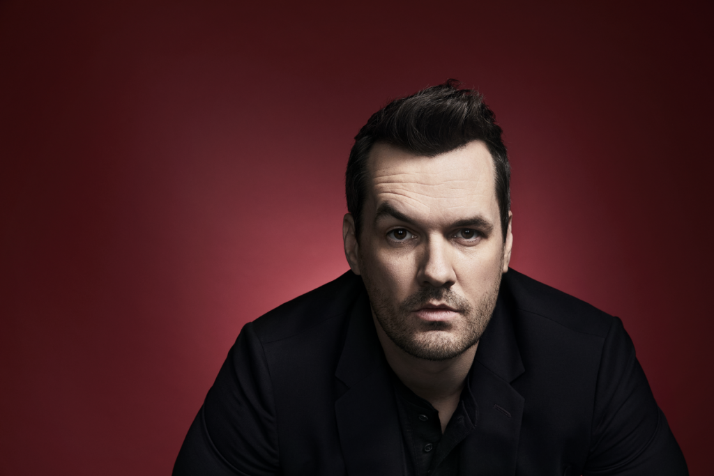 Jim Jefferies in a black shirt and raising an eyebrow.