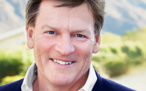Michael Lewis smiling in front of a lush hillside.