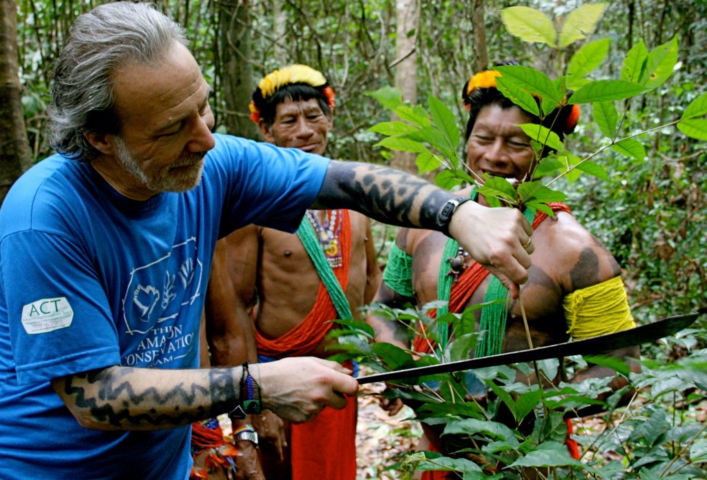 Dr. Mark Plotkin chopping a plant in the rainforest with two native tribesmen.